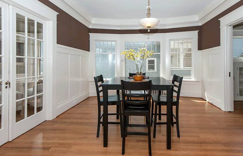 Two-toned dining area with white panels and windows with shutters