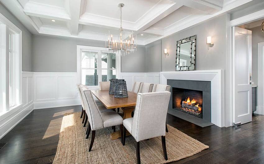 Dining room with upholstered chairs, solid french doors white wainscoting wood flooring and fireplace