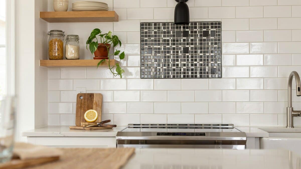 Dark gray mosaic inset panel centered in white subway tile above a stainless range