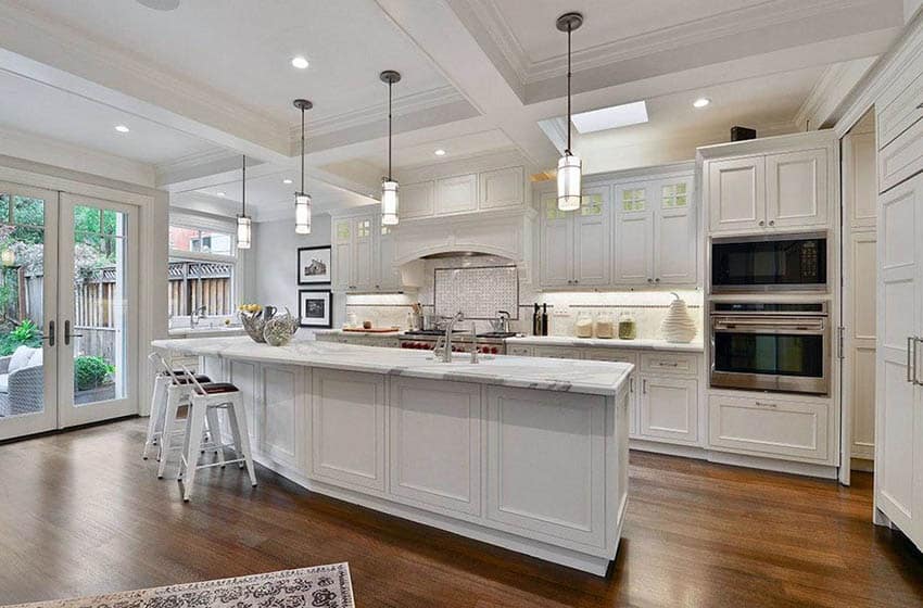 L layout kitchen with angled island, marble countertops and recessed cabinets