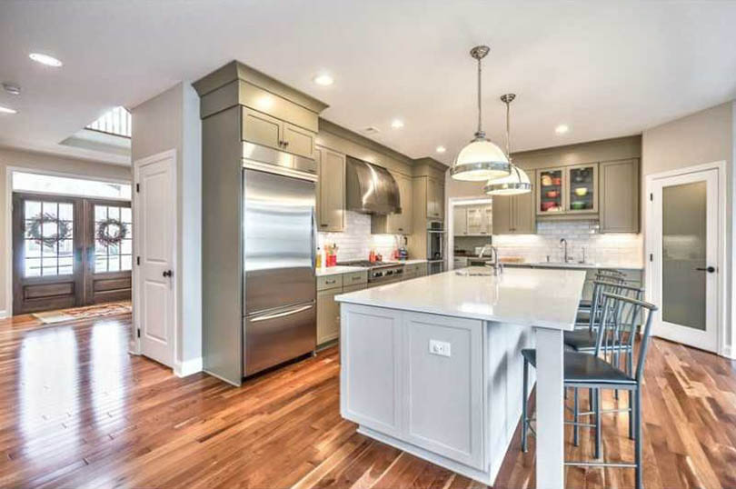 Traditional green cabinet kitchen with off-white color island and wood flooring