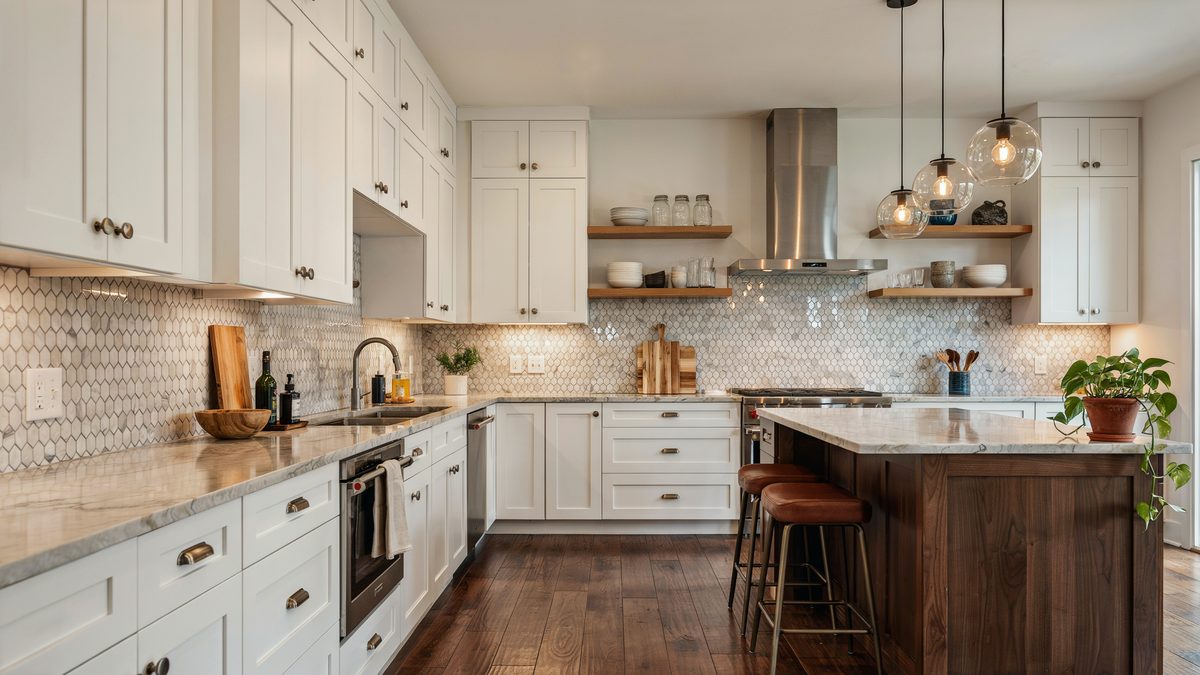 White perimeter cabinets with a walnut island and a small mosaic tile backsplash