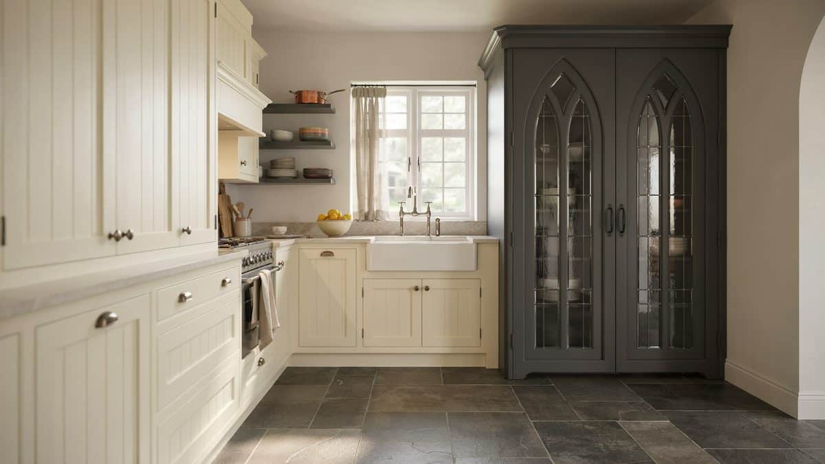 Cream beadboard cabinetry beside a charcoal arched glass cabinet on slate tile