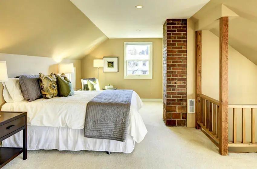 Attic bedroom with exposed brick fireplace and carpet