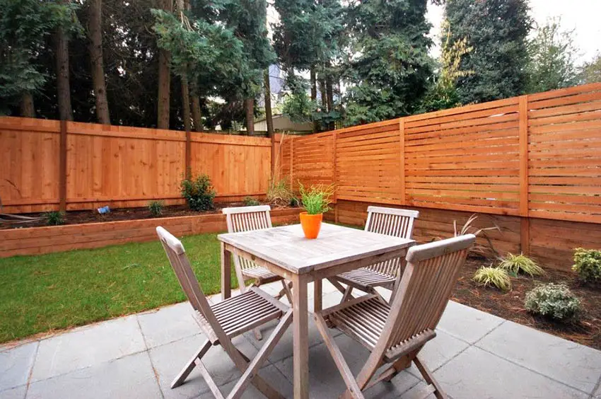 Backyard concrete patio with wood privacy fence and retaining wall