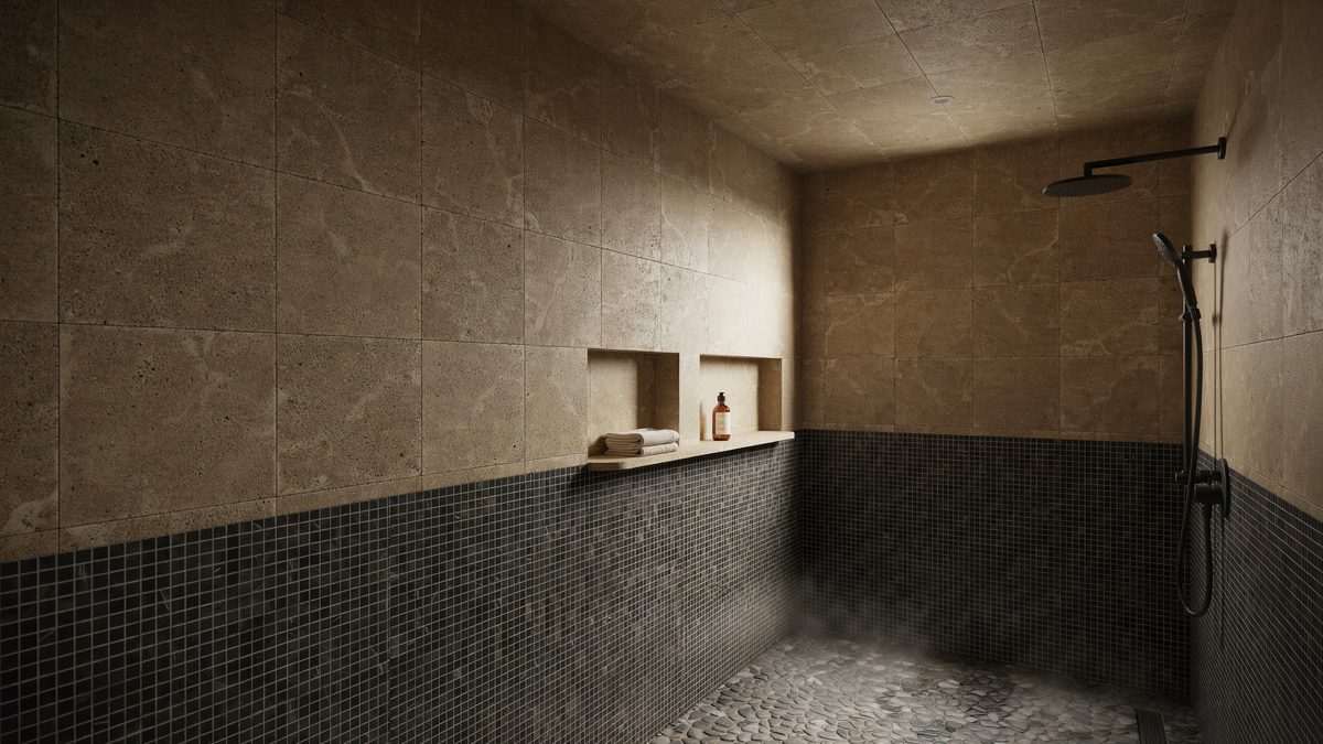 Dark mosaic wainscot below brown travertine walls with a pebble floor