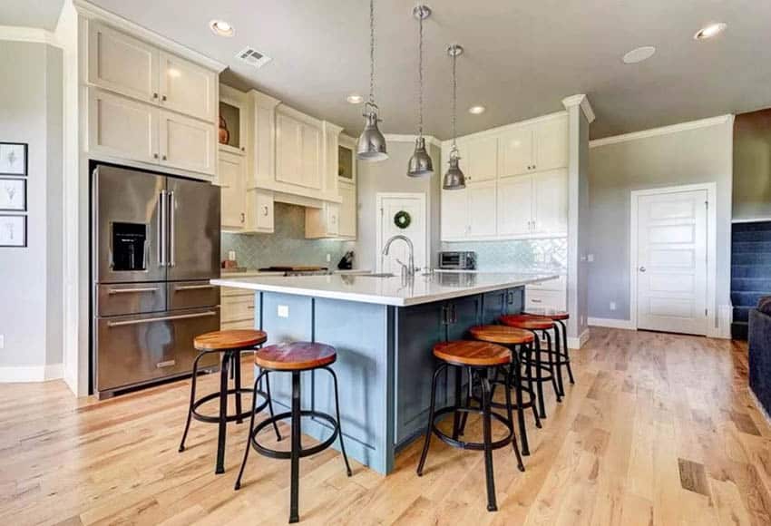 Blue kitchen island with seating white cabinets and pendant lights