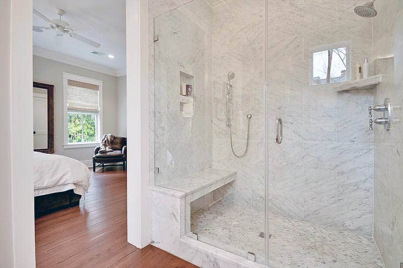 Carrara marble shower with glass door and bench