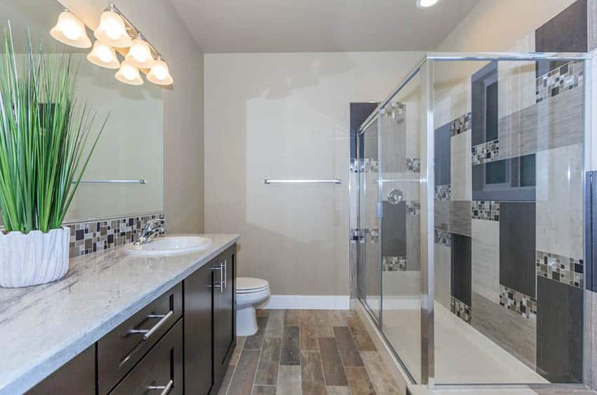 Contemporary 3/4 bathroom with white granite countertop and wood look porcelain tile floor and mosaic tile shower