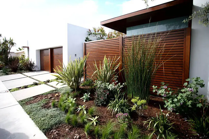 Contemporary driveway with horizontal wood slat fence in front yard