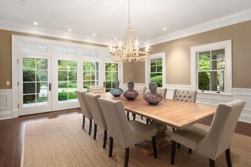 Dining room with tufted chairs wood table chandelier white french doors and wainscoting