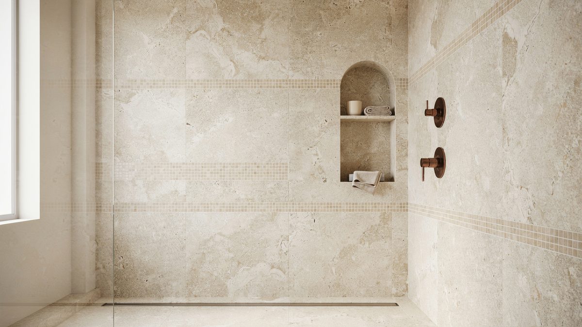 Arched niche carved into a pale travertine wall with bronze shower valves