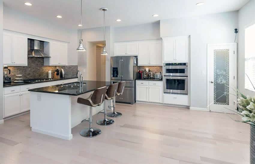 Kitchen with white cabinets and black granite countertops with birch wood flooring