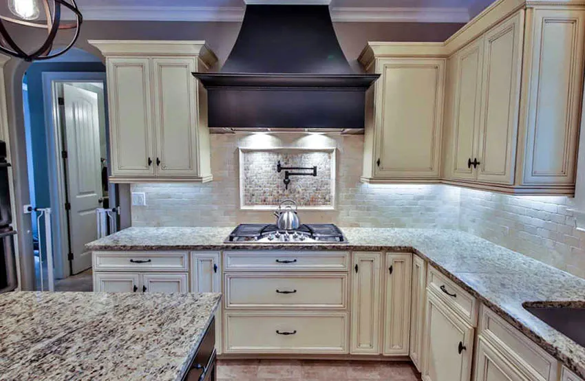 Kitchen with pot filler above stove top and distressed cabinets