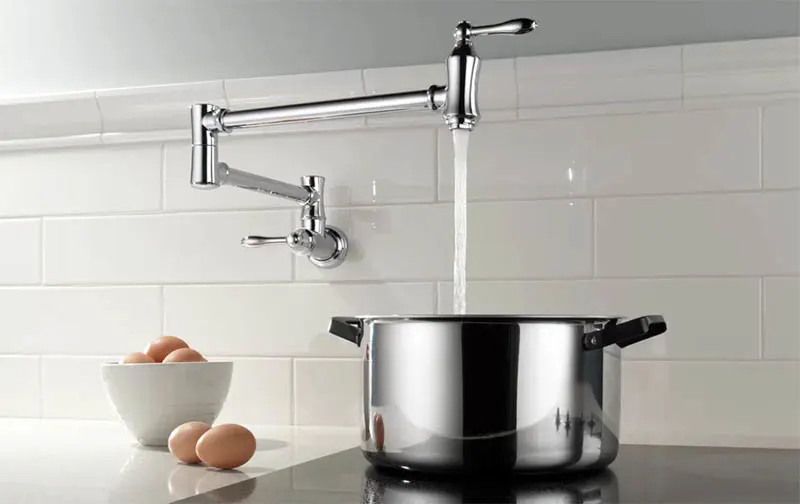 Kitchen with pot filler faucet over stove top with subway tile