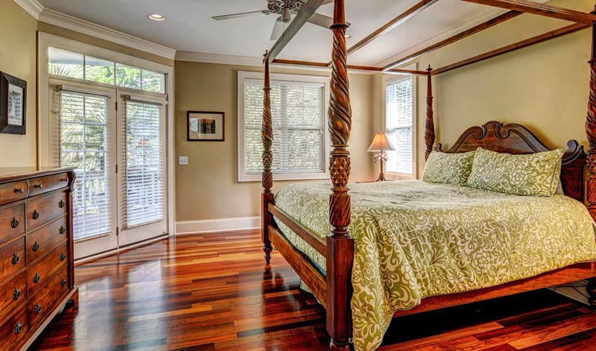 Bedroom with four posted bed, door with blinds and ceiling fan