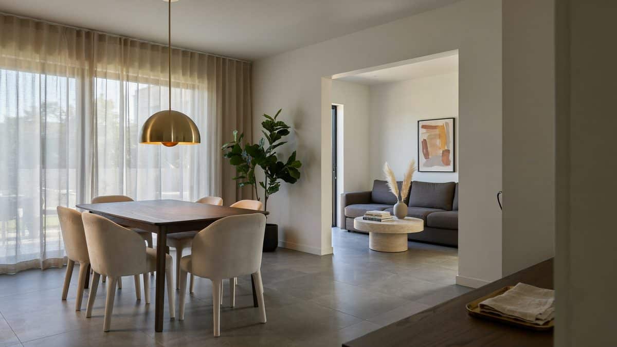 Round table under a brass dome pendant with the living room beyond