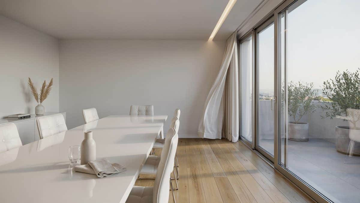 White dining table beside sliding glass doors opening to a bright balcony