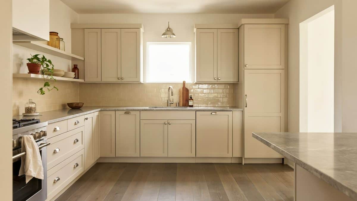 Oatmeal cabinets and tundra gray marble counters with ash wood flooring