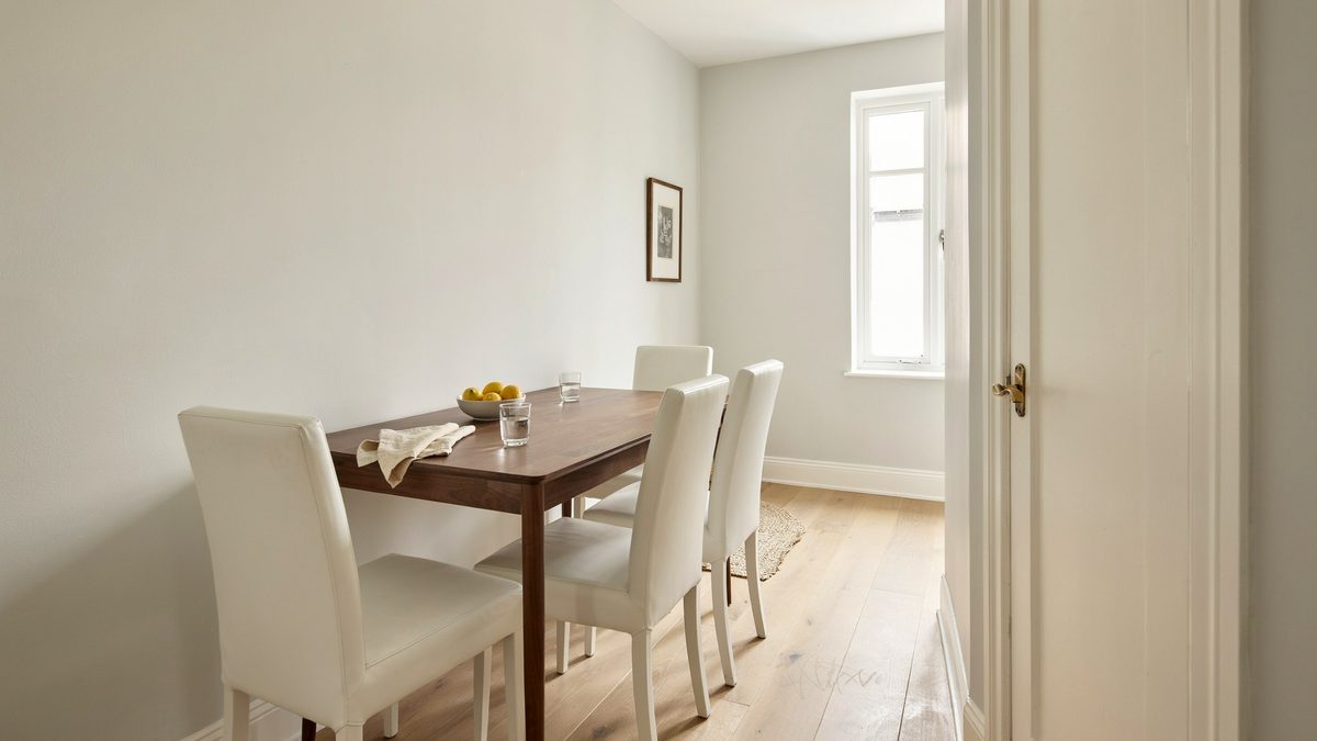 Compact dark table with white high back chairs tucked against a hallway wall