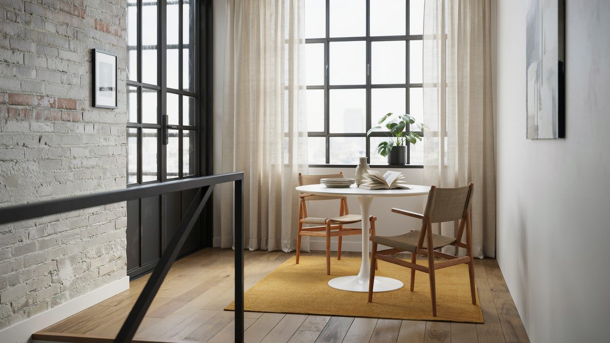 Small round table on a yellow rug beside black framed loft windows