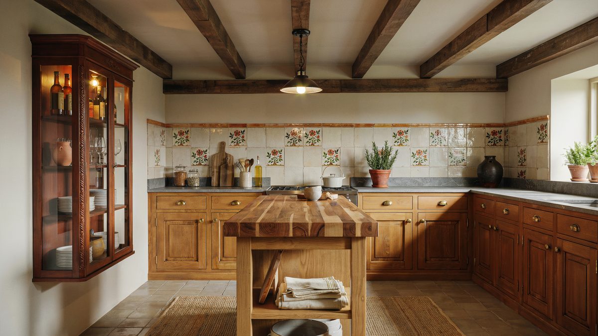 Carved mahogany cupboard beside beechwood cabinets and a butcher block kitchen island