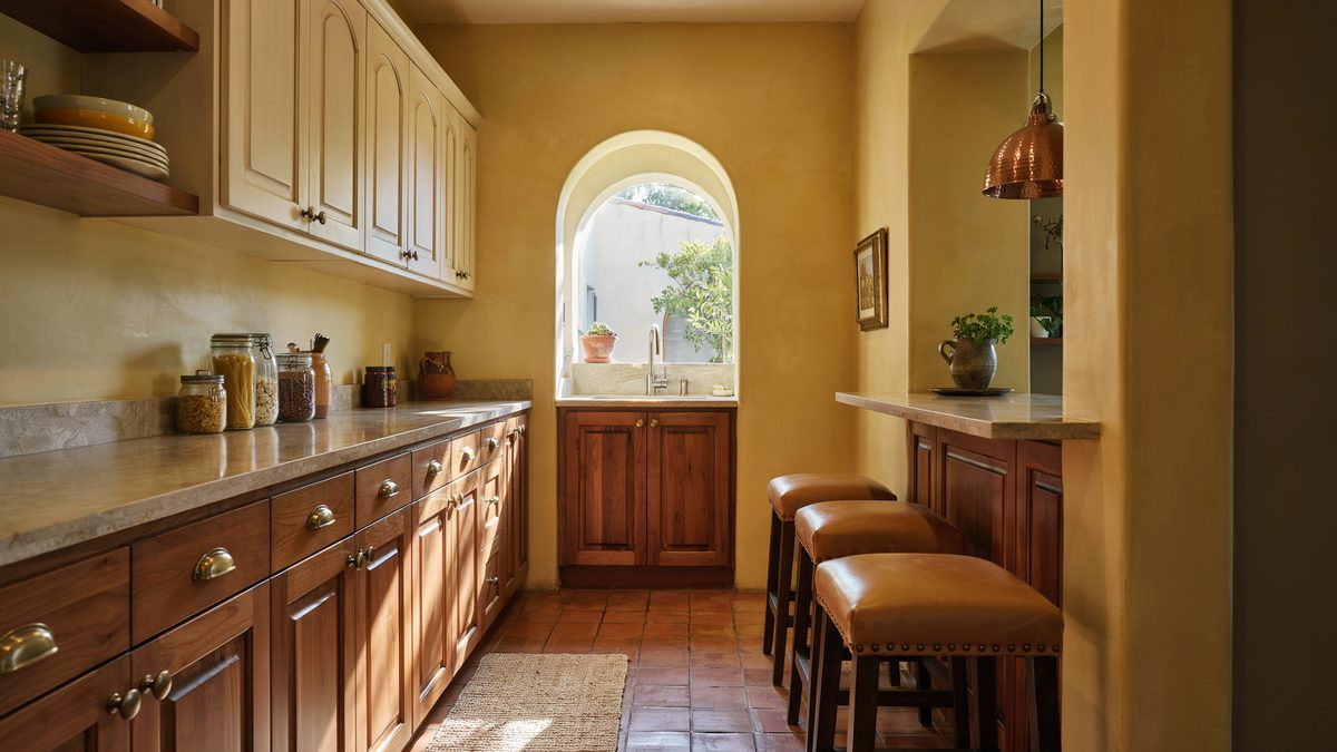 Mustard walls with mahogany and cream cabinets plus tan leather nailhead barstools