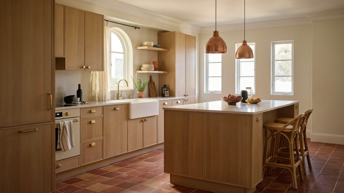 Matte walnut cabinets paired with white countertops, tall molding, and terracotta tile floors