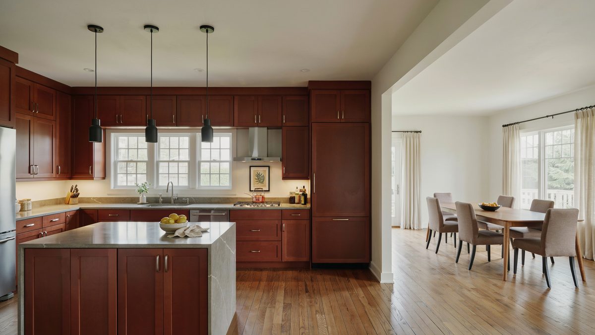 Solid mahogany cabinets paired with gray quartz counters and tall windows