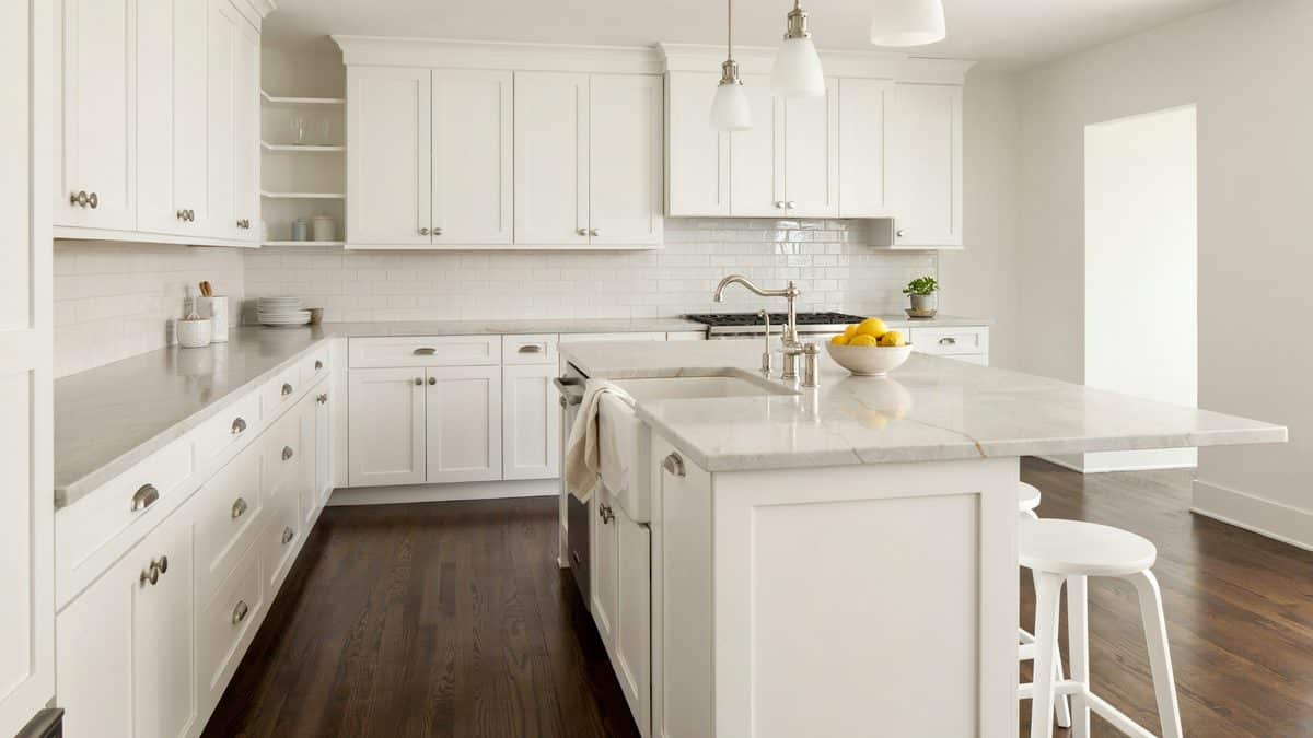 White cabinets and soapstone counters above dark walnut plank floors