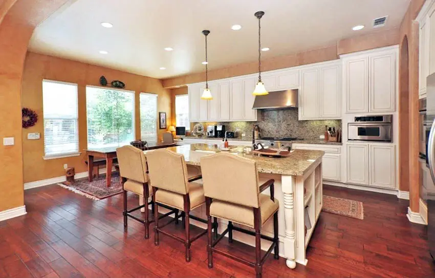 Traditional kitchen with cherry wood flooring white cabinets and beige granite counters