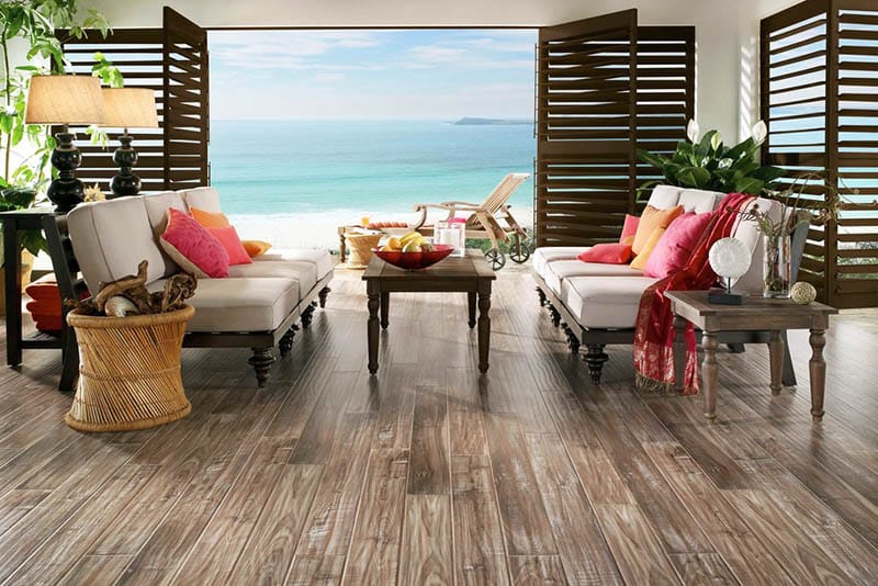 Room with view of the ocean, upholstered sofa, pink pillows and rattan side table