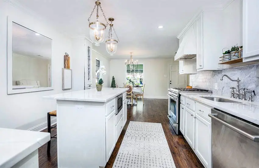 White kitchen with stainless steel faucet white marble look quartz countertops and shaker cabinets