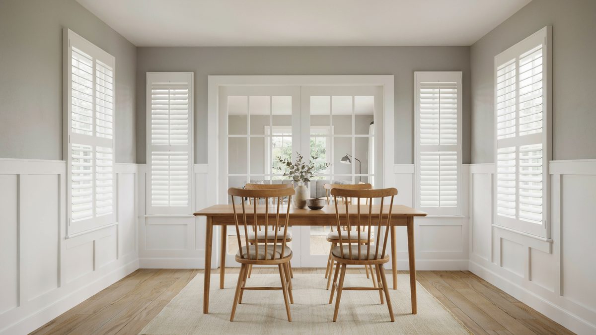 Spindle chairs and shutters in a gray and white paneled dining space