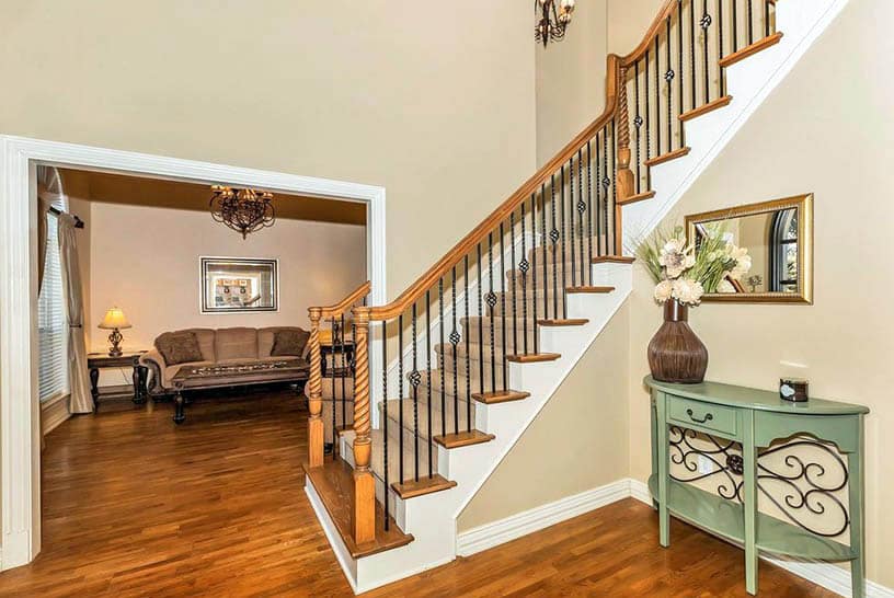 Foyer with classic staircase with twist design balusters and metal railing supports
