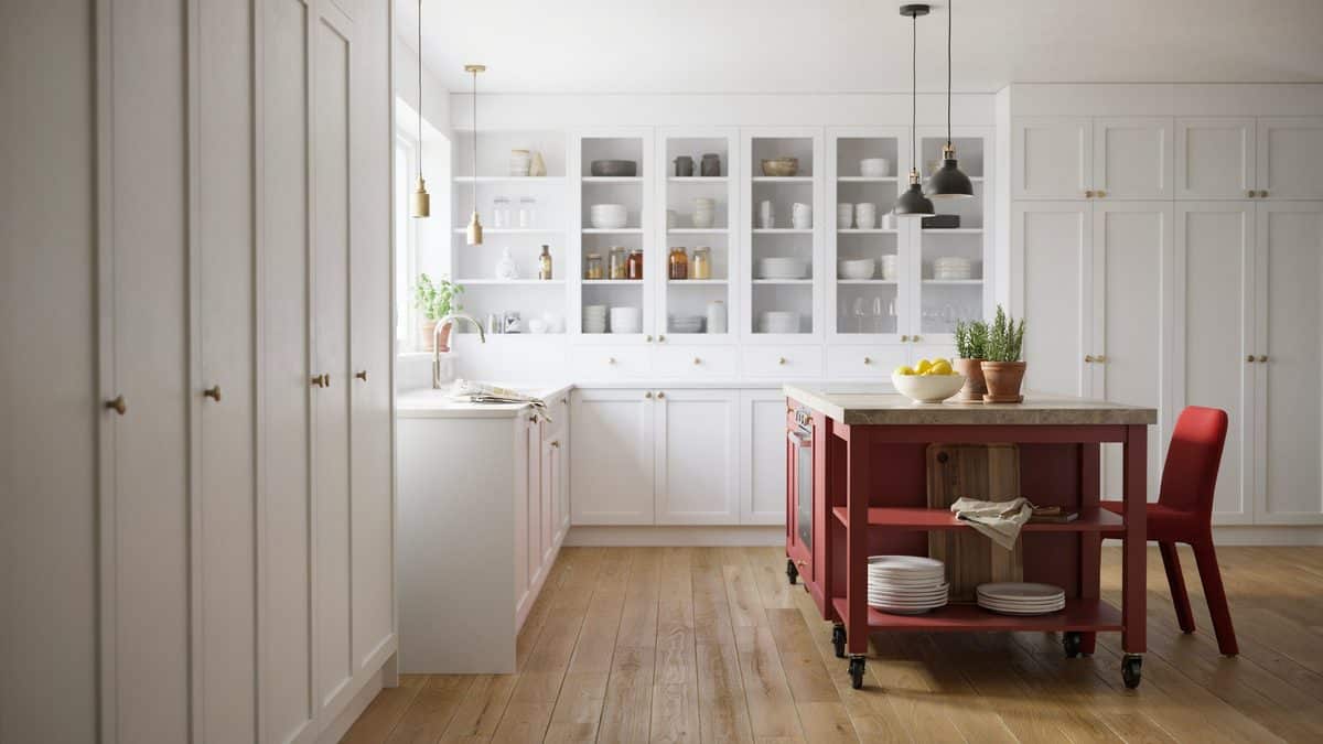 Red framed island with stone top beside glass front cabinets
