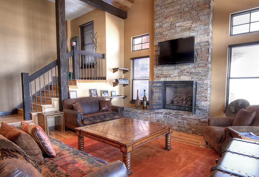Rustic room with granite fireplace, and dark brown couches