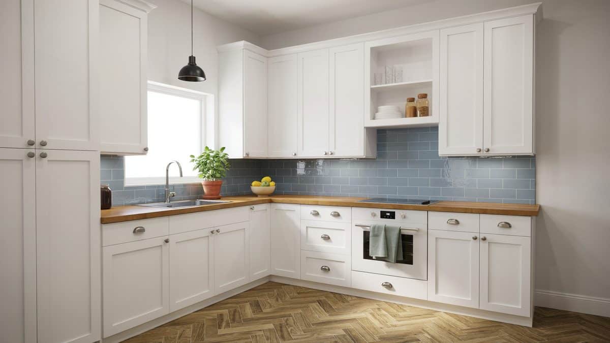 Blue subway tile backsplash with white shaker cabinets and butcher block counters