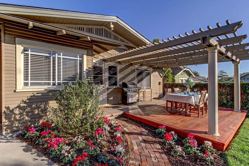 Large pergola idea with stained wood deck and a patch of flower garden