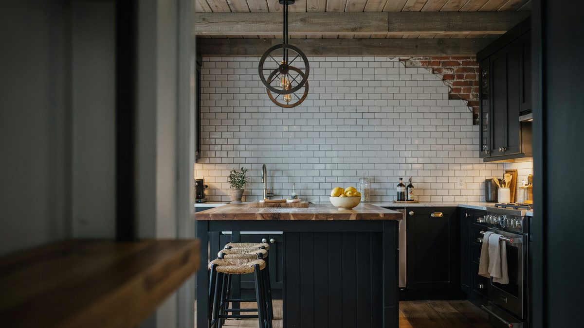 Navy cabinets and a brick accent wall behind a thick rustic slab counter