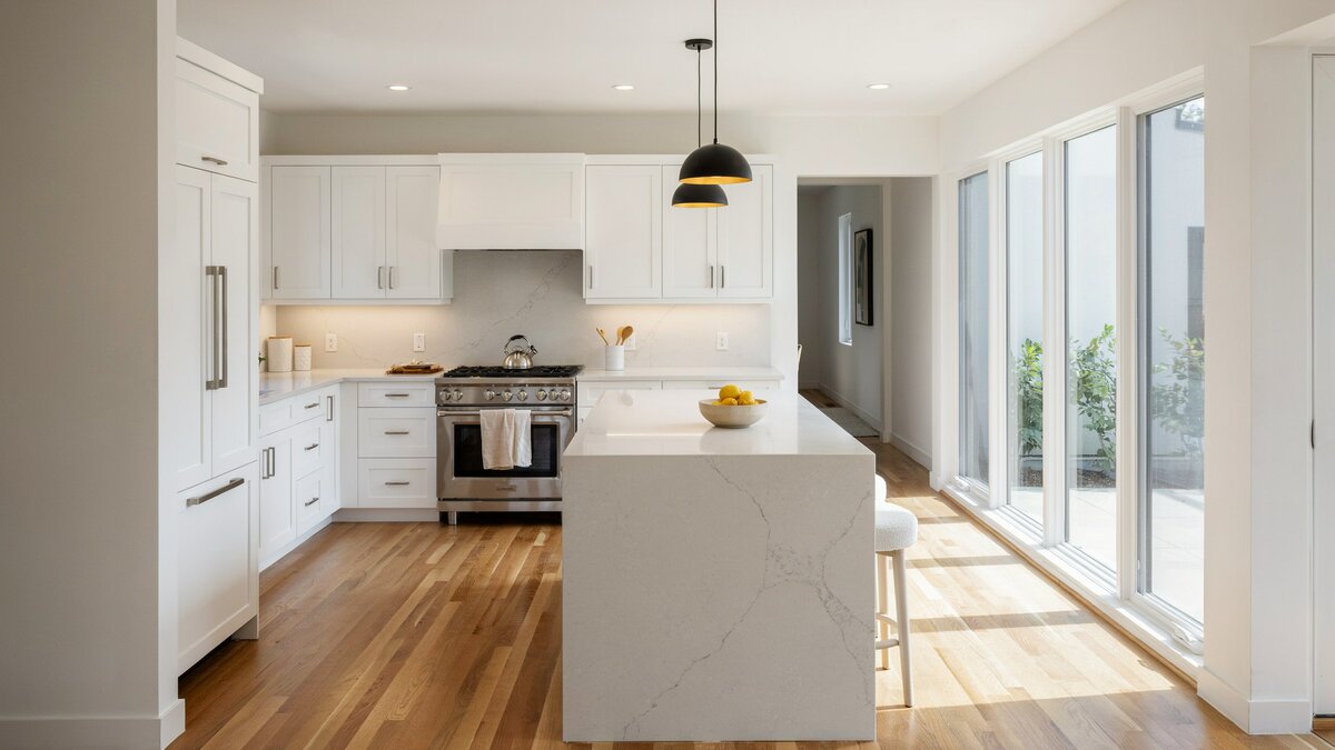 All white compact kitchen with a pro gas range and sliding glass doors