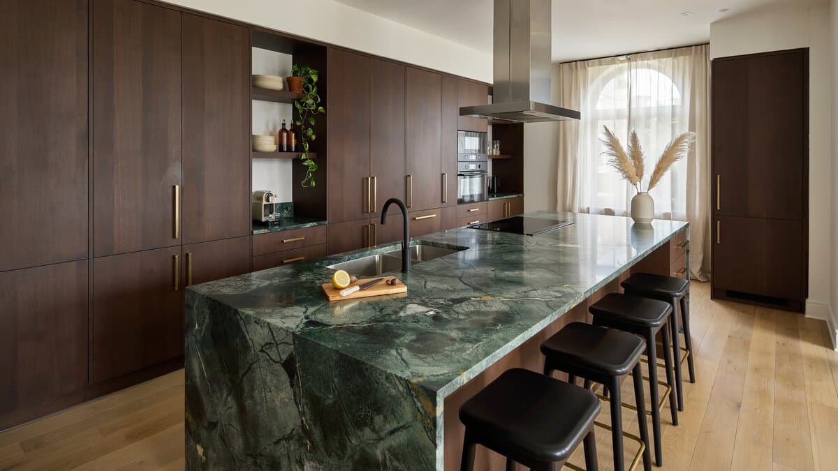 Long mahogany storage wall paired with an equally long polished stone island