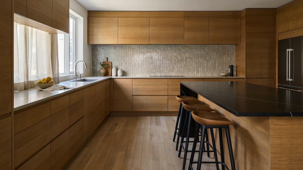 Horizontal wood grain laminate cabinets behind a black quartz topped narrow island