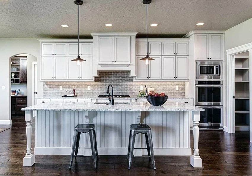 Cottage kitchen with beadboard island white shaker cabinets and dark wood flooring