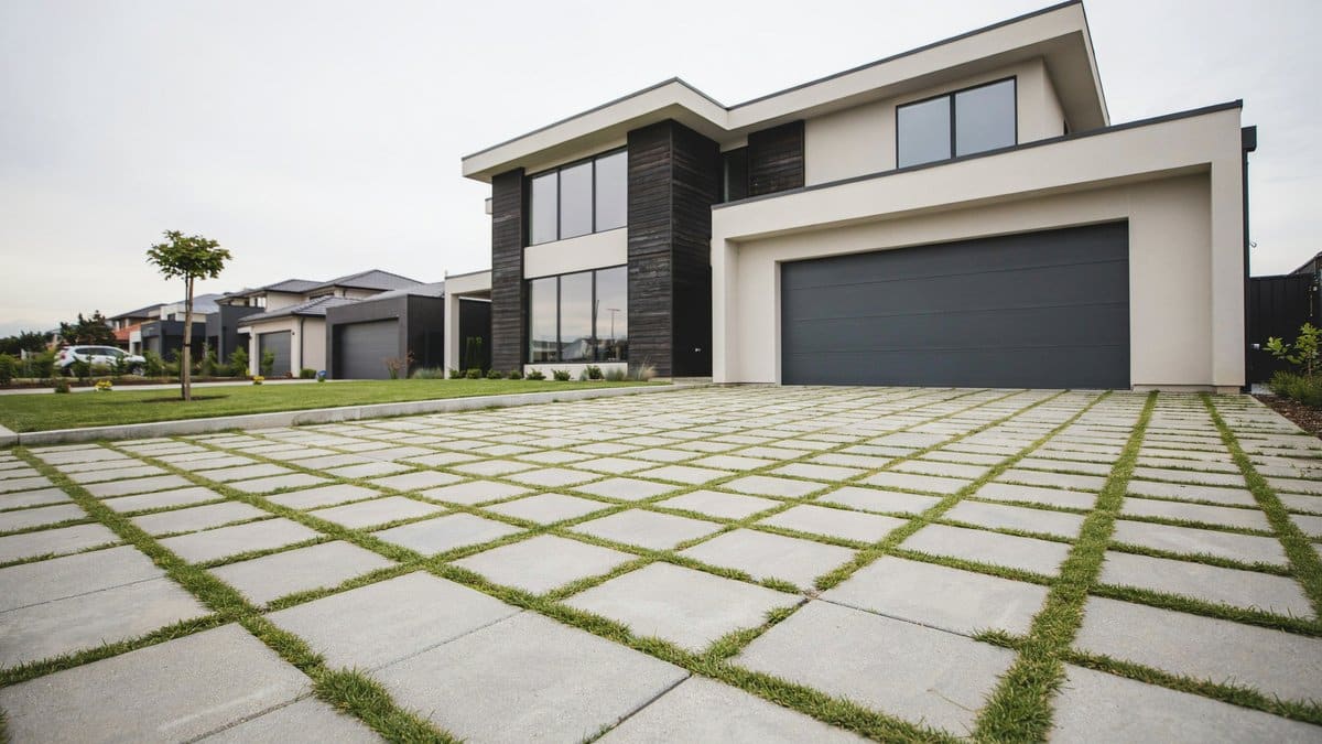 Square pavers with grass joints forming a grid driveway at a modern white home