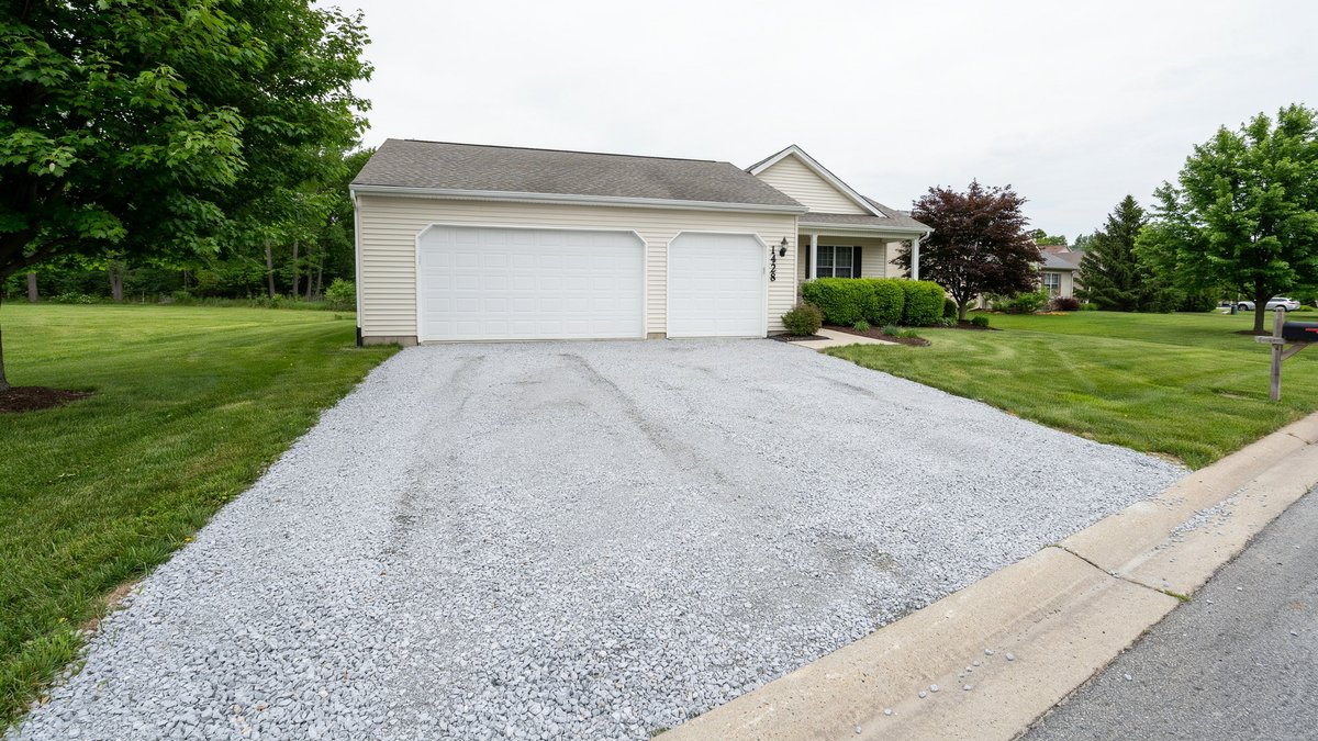 Light crushed stone driveway with green lawn on both sides at a ranch home