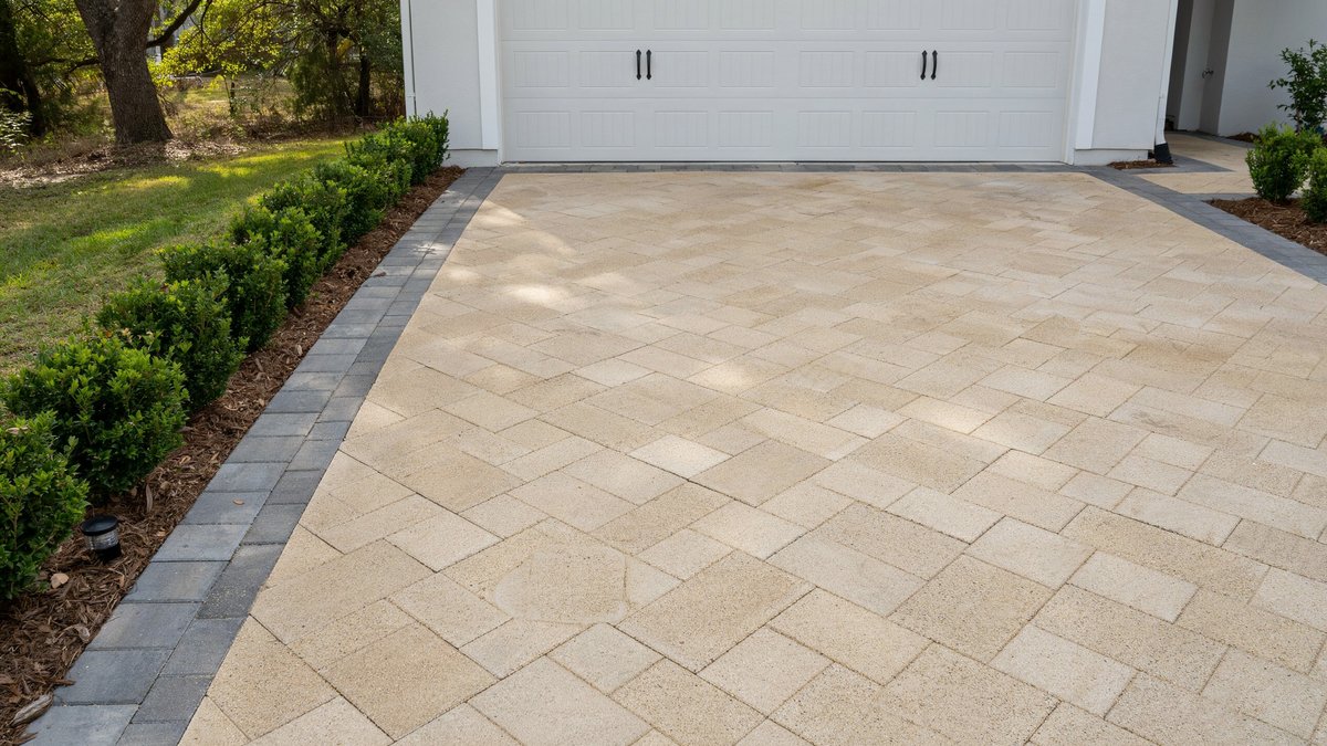 Cream interlocking concrete pavers with charcoal border running up to a white garage