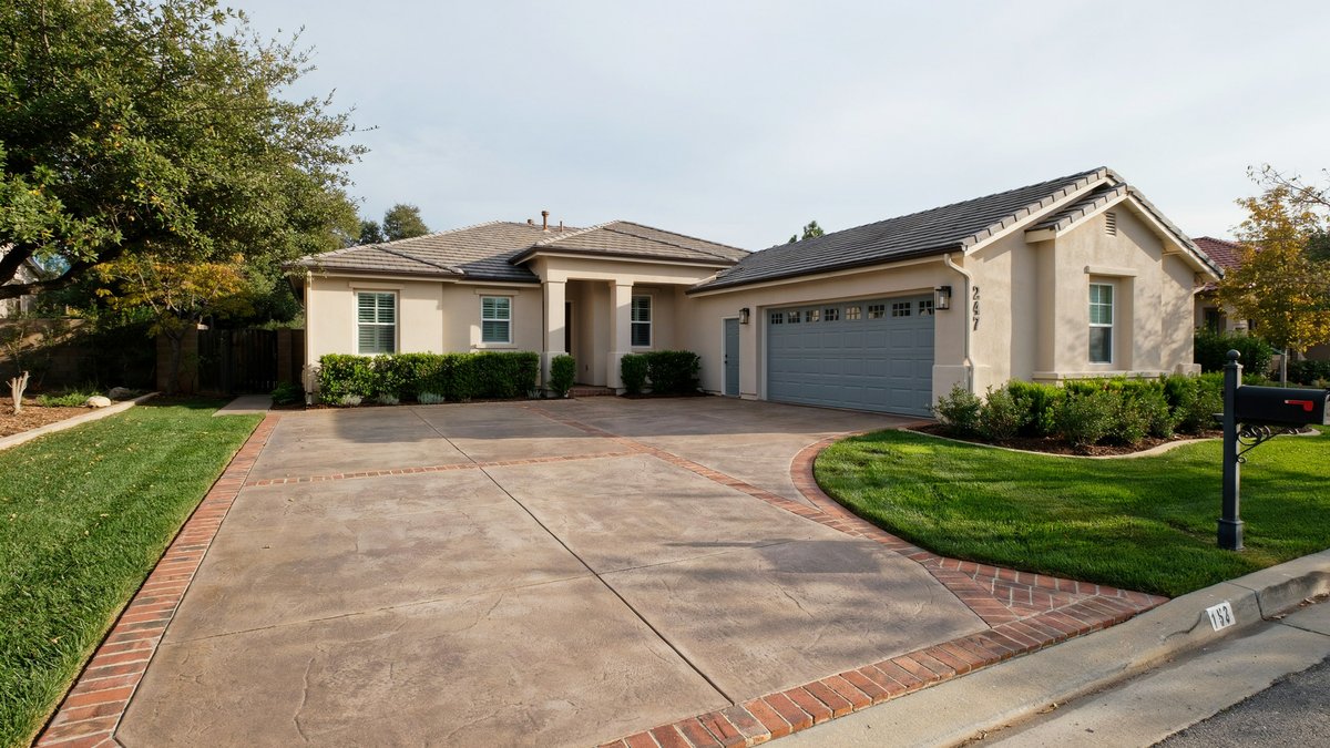Poured concrete center panel edged with red brick pavers at a stucco ranch home