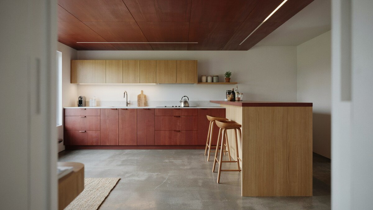 Mahogany dropped ceiling above a raised breakfast bar island and concrete floors