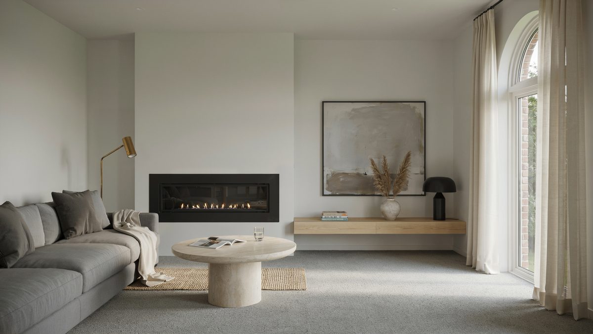 Wall to wall gray carpet framing a low gray sectional and linear glass fireplace